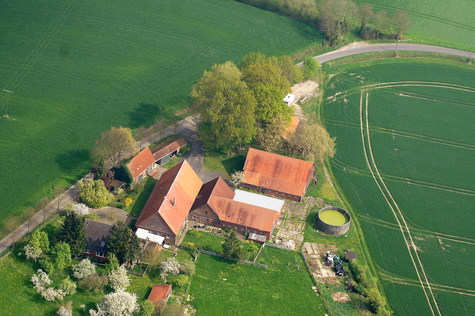 Luftaufnahme einer Hofstelle mit rotem Ziegeldach zwischen Ackerflächen im Münsterland